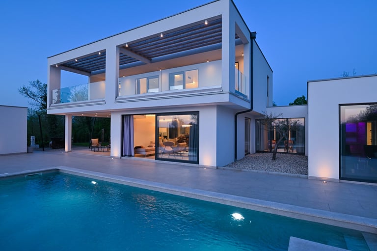 Exterior view of a modern luxury house with a swimming pool at twilight.